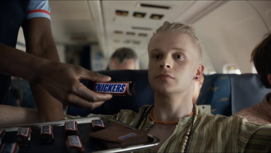 Một người đàn ông được tiếp viên cho 1 thanh snickers thấy rõ nhãn.