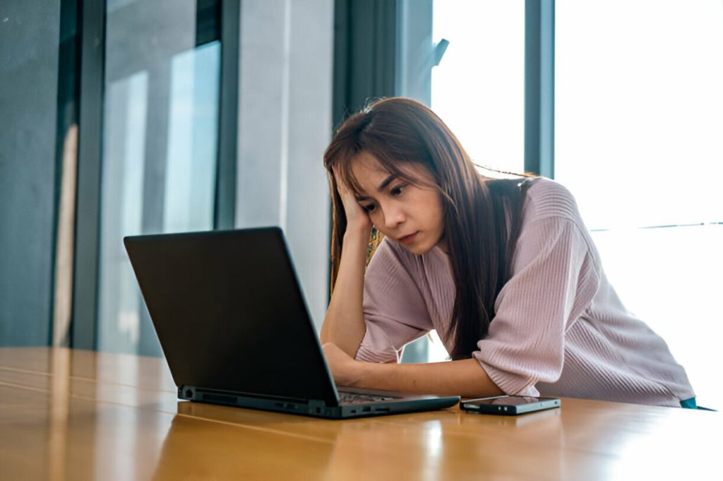 Một người phụ nữ đang nhìn màn hình laptop và cảm thây mệt mỏi.