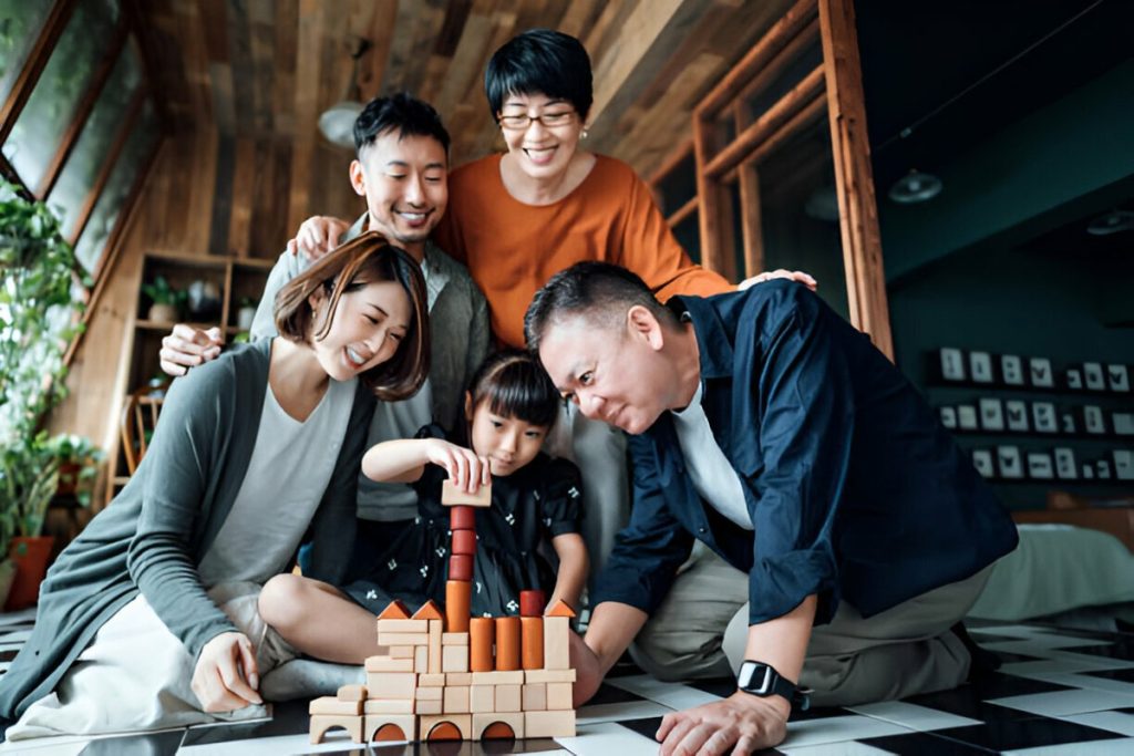 Một gia đình châu Á đang chơi trò chơi xếp hình gỗ.