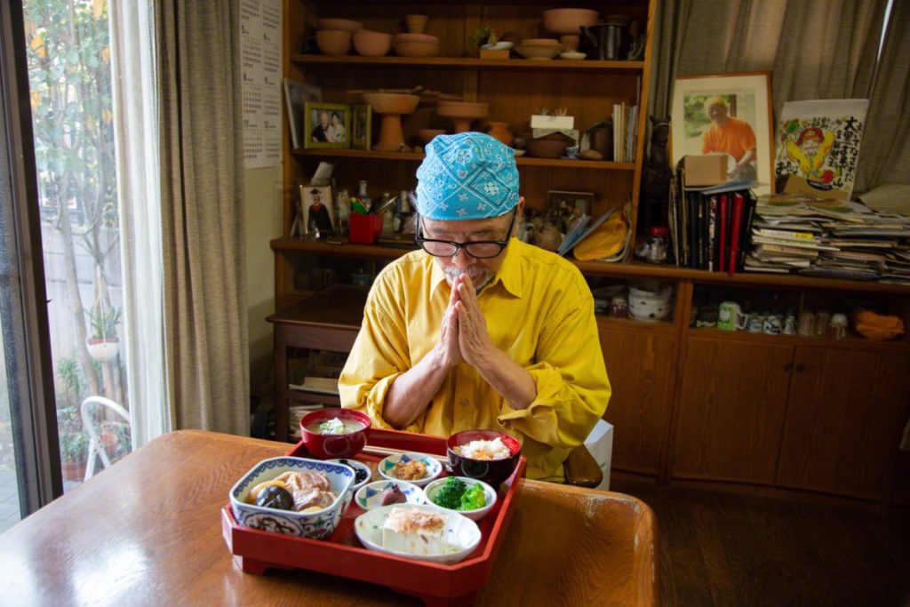 Ông Nagayama Hisao ngồi chắp tay trước bữa ăn thịnh soạn, đặt trong mâm